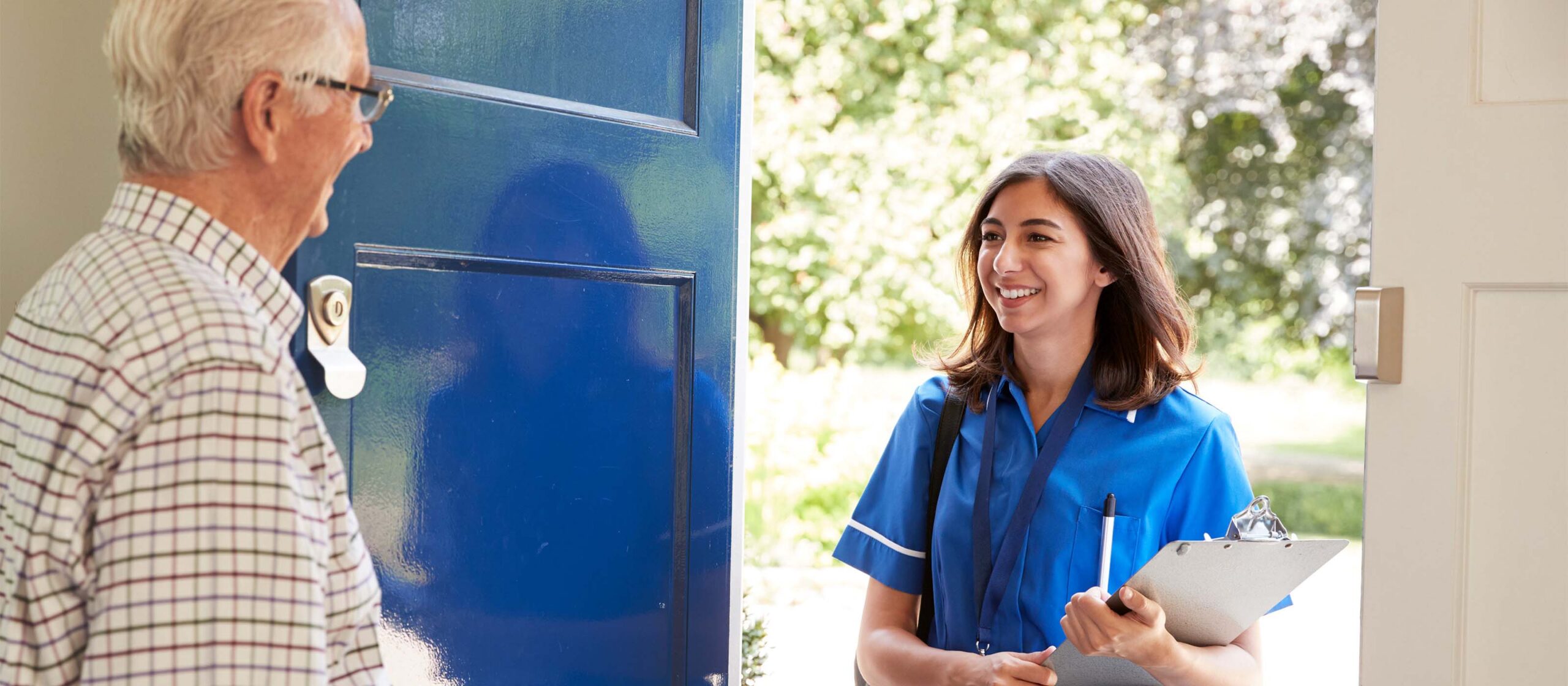 Senior man greeting female nurse making home visit